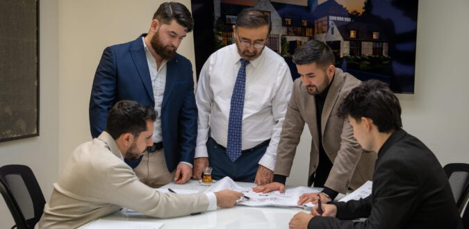 Aria Build team reviewing architectural drawings around a conference table.